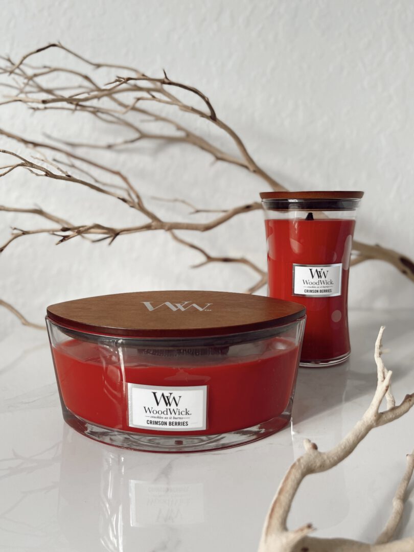Een foto van een roodachtige WoodWick kaars met de geur van Crimson Berries, uitstralend een warme en fruitige sfeer in de kamer. Thuis bij Serena